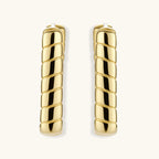 Chunky segmented gold-plated huggie hoop earrings with bamboo-inspired geometric design on white background.