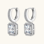 Sterling silver huggie hoops with emerald-cut moissanite drops featuring pavé-set crystals on white background.