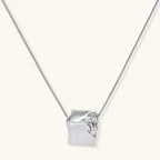 Close-up of a silver-toned molten cube pendant necklace with organic flowing texture on a minimalist chain