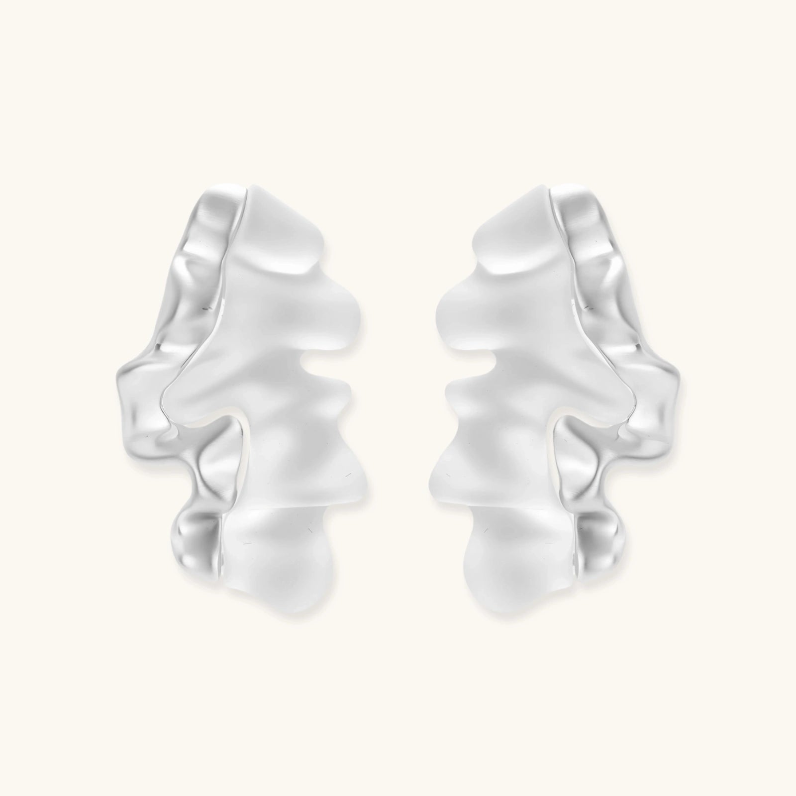 Pair of silver-toned sculptural earrings with flowing abstract forms and stud backs against white background.