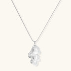 Modern sculptural pendant necklace with twisted metallic design on delicate silver chain against neutral background.